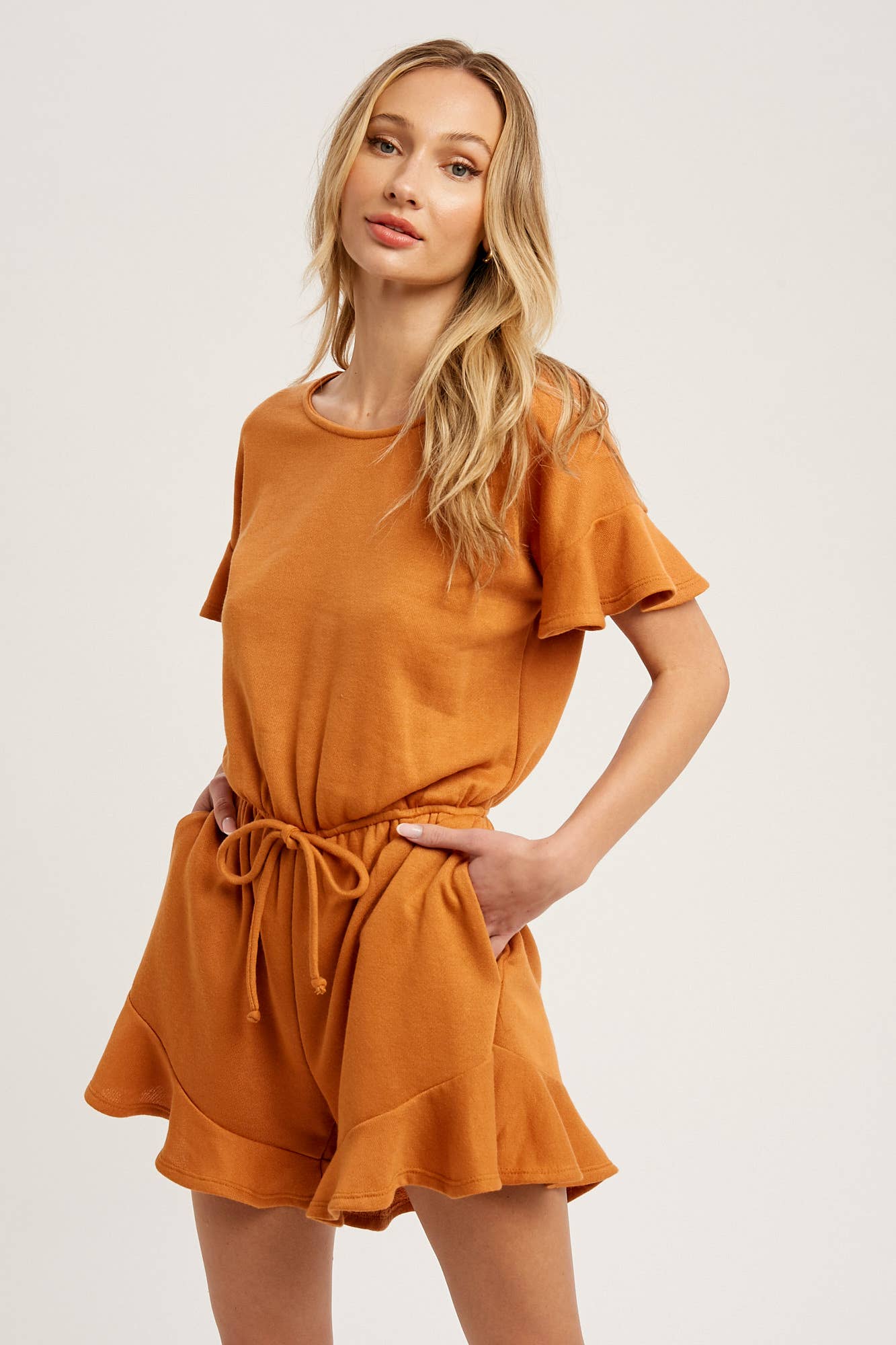 Soft French terry romper with ruffled sleeves, elastic waist, pockets & back button closure. Comfy, cute, and perfect for sunny days or casual outings.