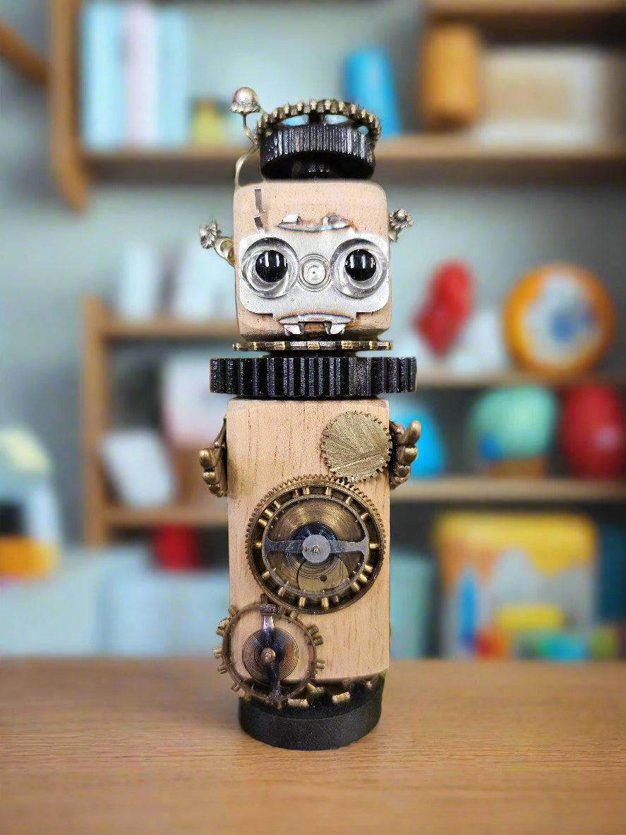 The Handmade Wood Block Steampunk Robot is a unique, decorative figurine crafted from wood with an aged, rustic look. Each robot is one-of-a-kind for display only. Includes a heart-shaped balloon. Available in various sizes, it&