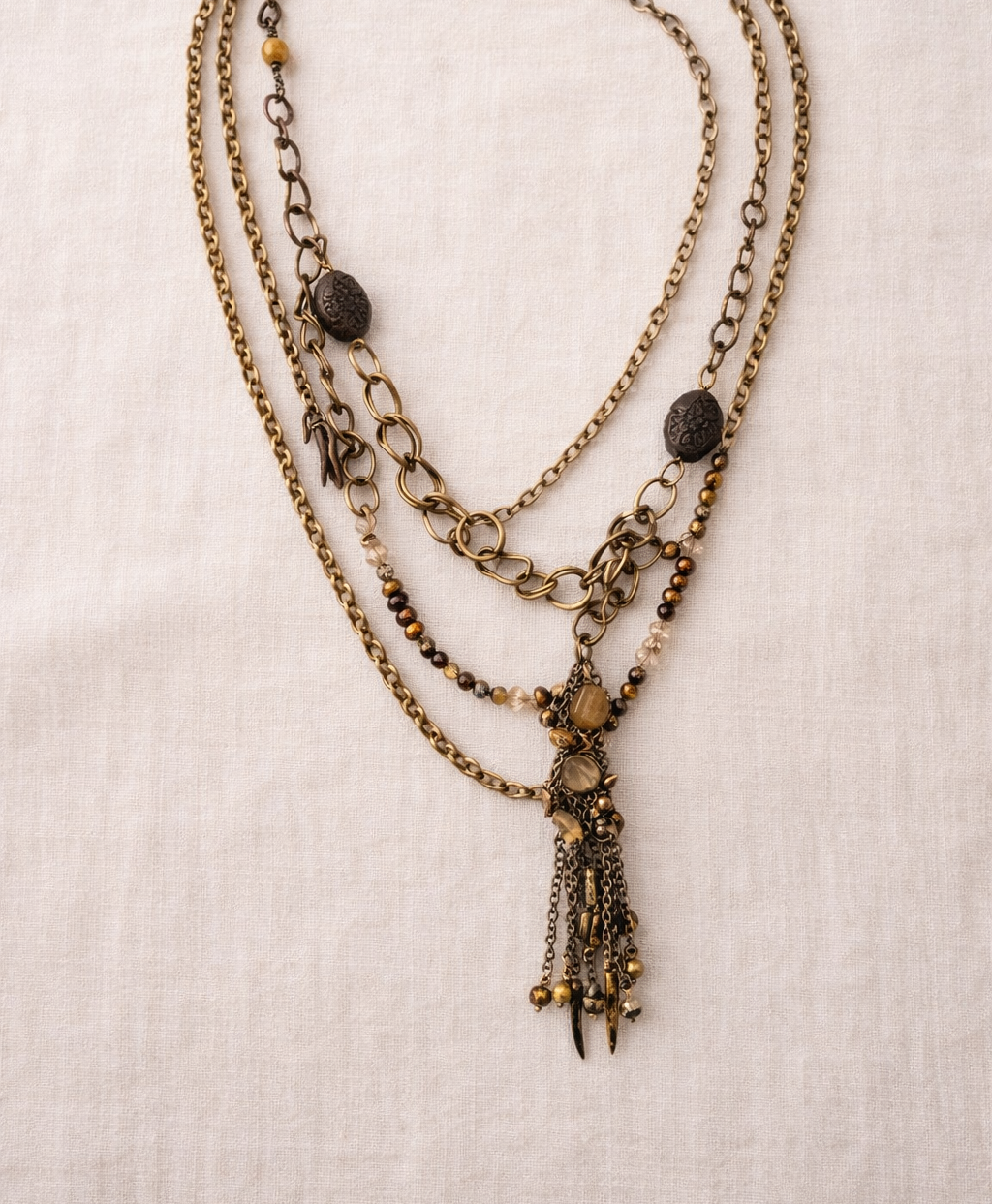 Layered antique-style chains with earthy beads and a charm tassel. The Nomad Layer Necklace is a soulful, wander-inspired statement.