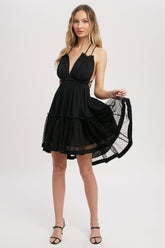 Black gauze swing mini dress with halter tie bust, backless design, elastic waist, and mesh ruffle hem. Lightweight summer party dress.