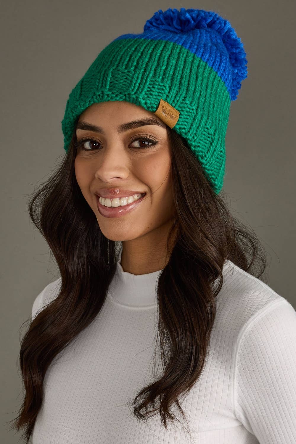 Blue and green color block pom hat by Panache Apparel Co. Made from 100% acrylic with cozy fleece lining and a large pom for cheerful winter style.