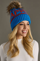 Blue and orange Après knit hat with a natural-toned faux fur pom and cozy fleece lining. Made from 100% acrylic for colorful, comfortable winter style.