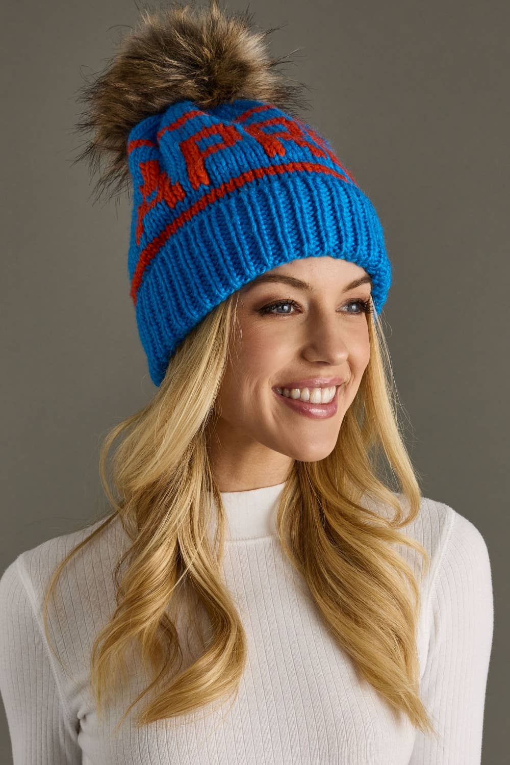 Blue and orange Après knit hat with a natural-toned faux fur pom and cozy fleece lining. Made from 100% acrylic for colorful, comfortable winter style.