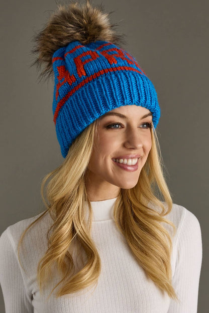 Blue and orange Après knit hat with a natural-toned faux fur pom and cozy fleece lining. Made from 100% acrylic for colorful, comfortable winter style.