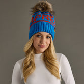 Blue and orange Après knit hat with a natural-toned faux fur pom and cozy fleece lining. Made from 100% acrylic for colorful, comfortable winter style.