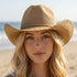 Braided cord band cowboy hat featuring woven paper straw texture and soft curved brim. Lightweight boho western style perfect for beach days, festivals, and summer outfits.