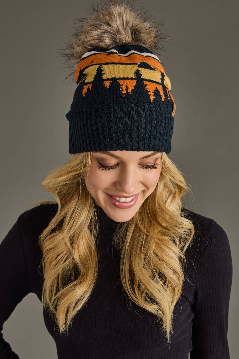 Dark navy knit hat with forest landscape design & natural faux fur pom. Warm, stretchy, and stylish—crafted from 85% acrylic & 15% spandex for comfort.