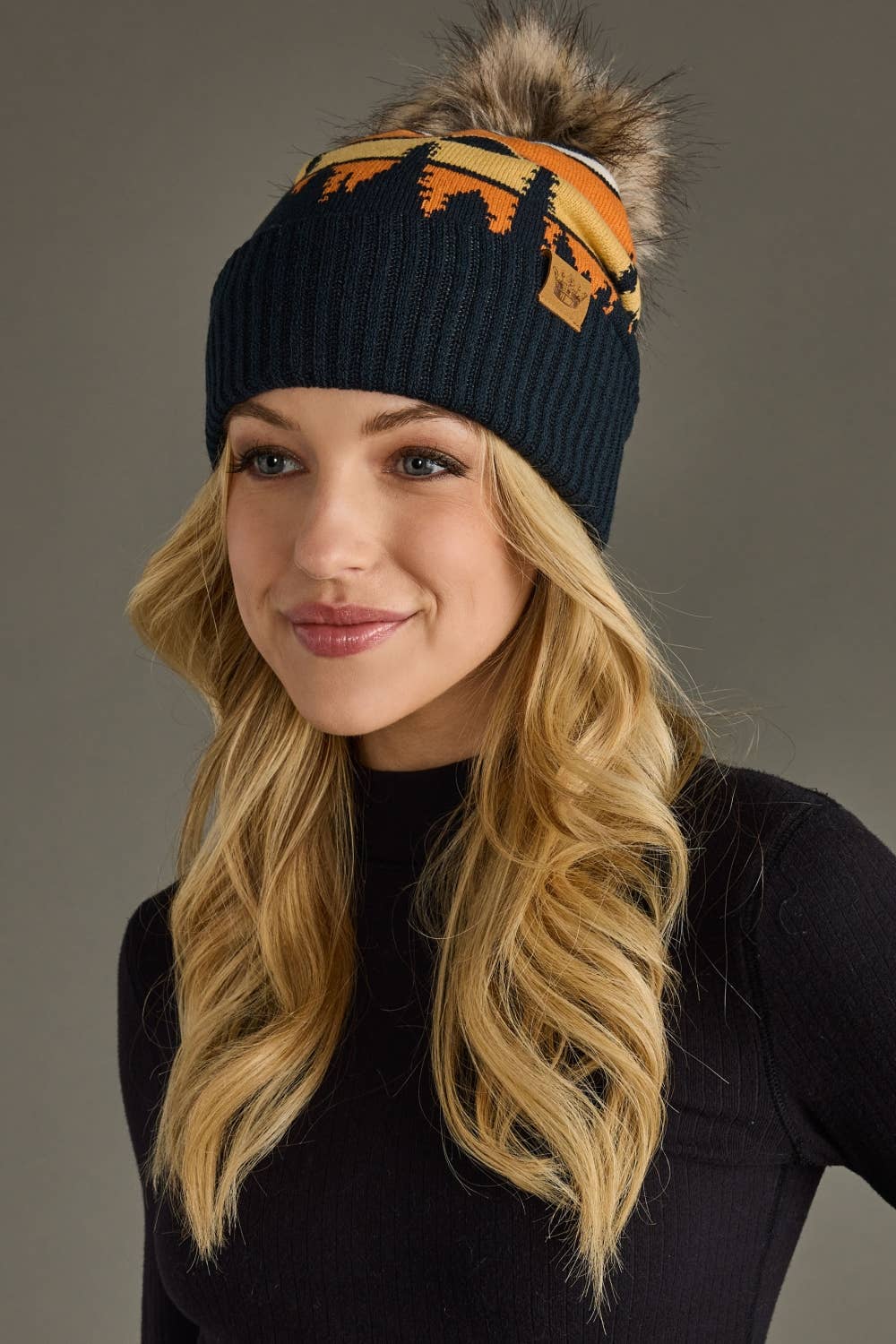 Dark navy knit hat with forest landscape design &amp; natural faux fur pom. Warm, stretchy, and stylish—crafted from 85% acrylic &amp; 15% spandex for comfort.