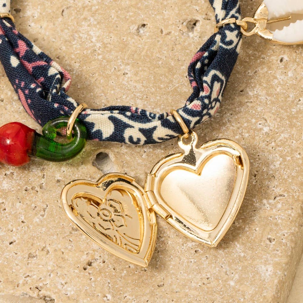 Heart Locket &amp; Charms Bandana Bracelet featuring a heart locket, cowrie shell, feather, and seaside-inspired charms on a vintage-style fabric band.