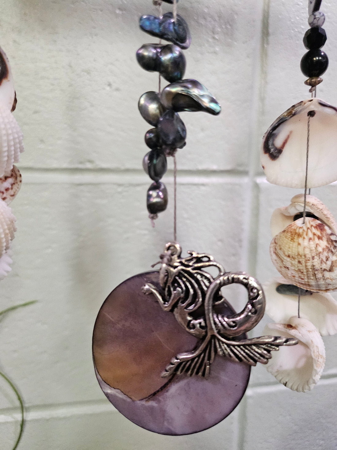 Add coastal charm to your space with the Shell &amp; Bead Bohemian Suncatcher. Handcrafted with natural shells, semi-precious stones, and beads, it captures sunlight to create a stunning display of light and texture, perfect for windows, gardens, or as a unique, nature-inspired gift.