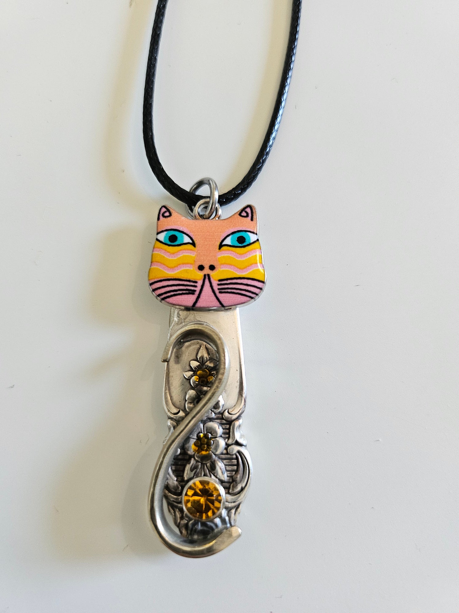 Handcrafted vintage silverware necklaces featuring enamel cat faces on adjustable satin cords. Made from 1951 Distinction and 1952 Primrose patterns.