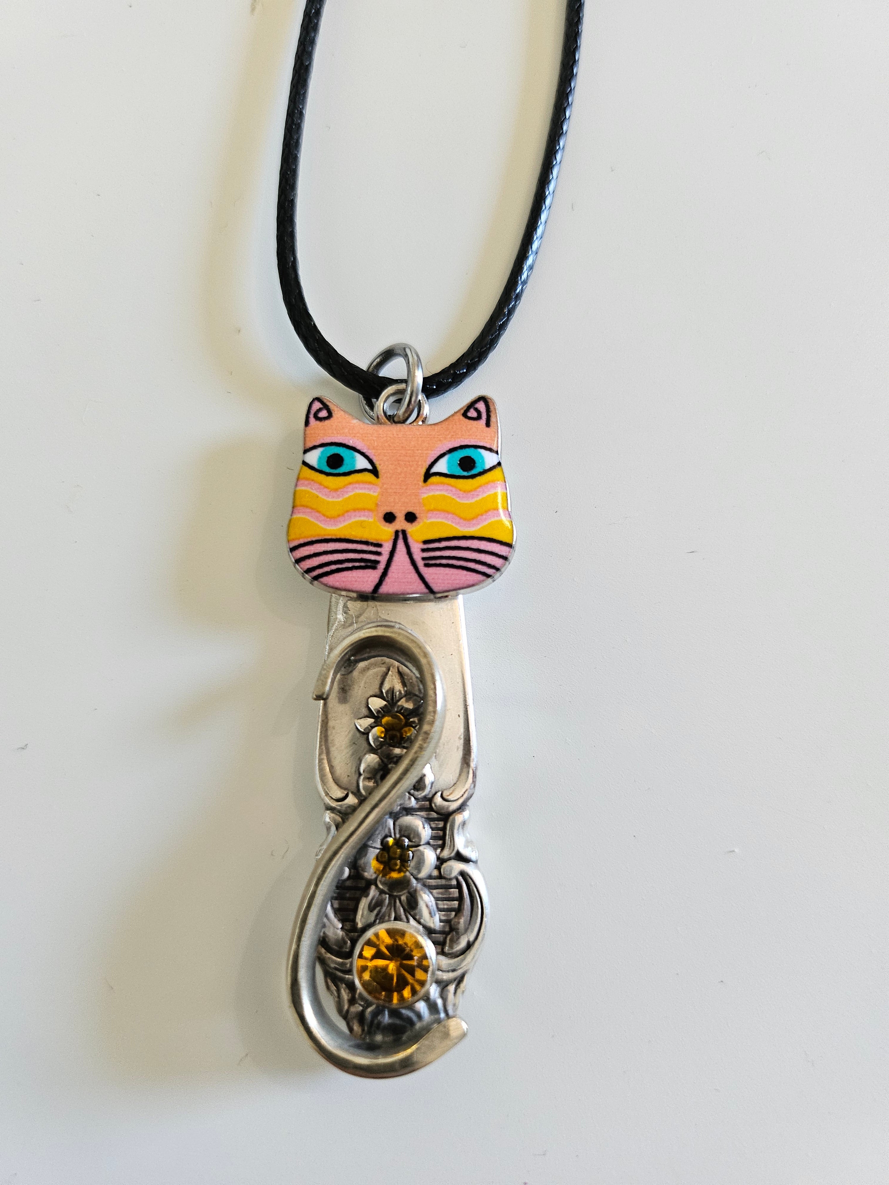 Handcrafted vintage silverware necklaces featuring enamel cat faces on adjustable satin cords. Made from 1951 Distinction and 1952 Primrose patterns.