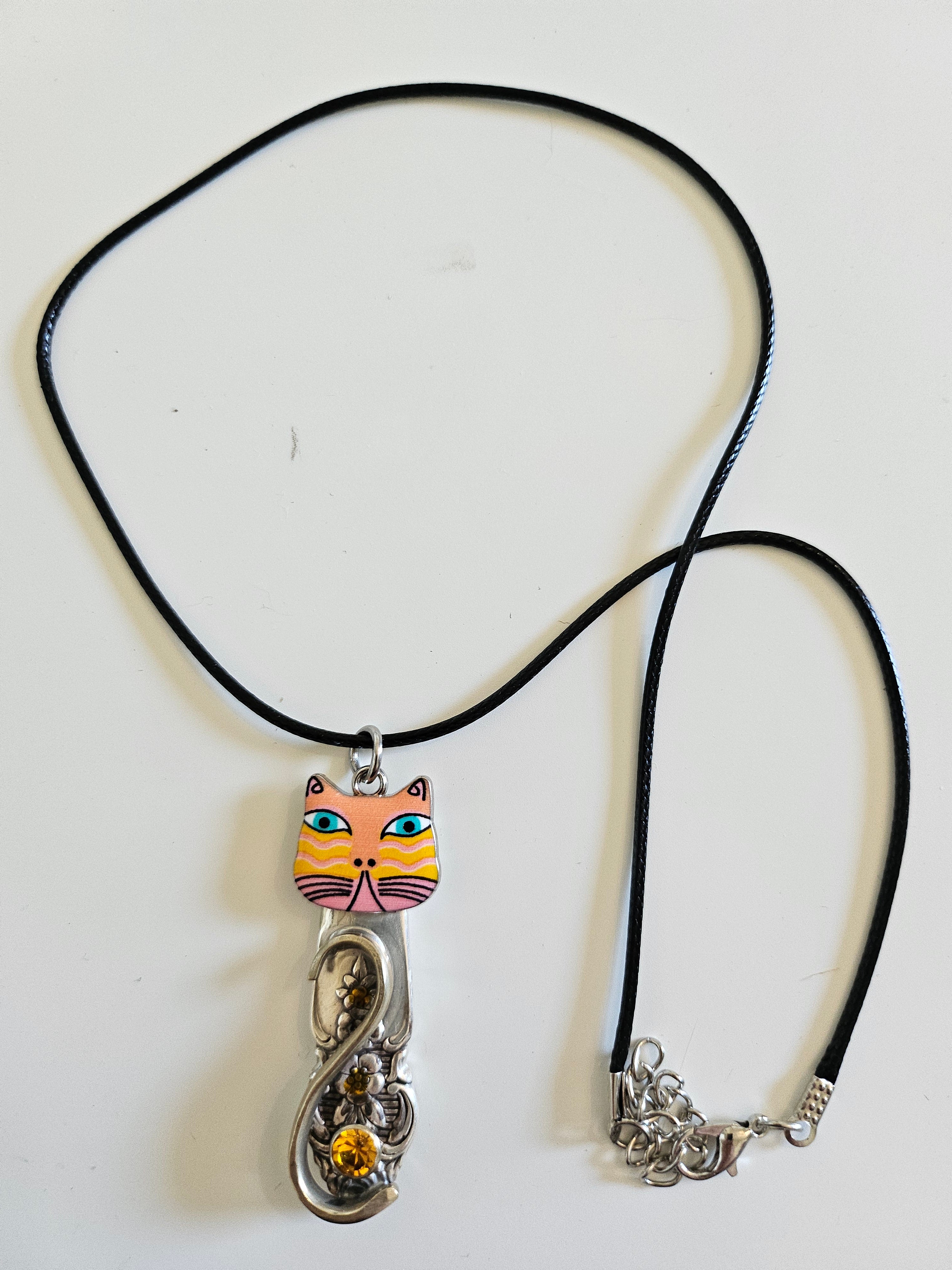 Handcrafted vintage silverware necklaces featuring enamel cat faces on adjustable satin cords. Made from 1951 Distinction and 1952 Primrose patterns.