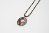 Handcrafted nature scene necklaces with real botanicals in iridescent and clear resin. Unique, wearable landscapes on chain or satin cord.