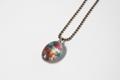 Handcrafted nature scene necklaces with real botanicals in iridescent and clear resin. Unique, wearable landscapes on chain or satin cord.