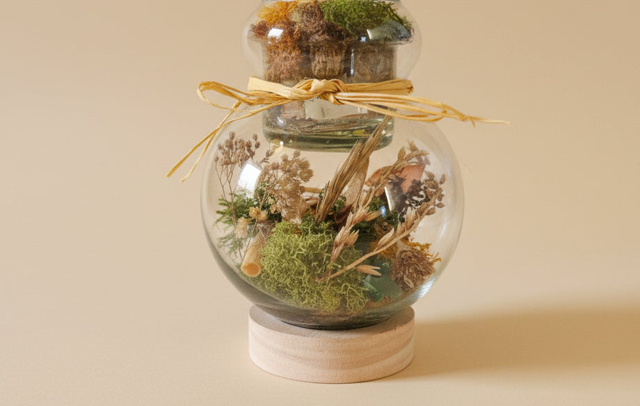 Glass hurricane lantern with a real butterfly, dried autumn flowers, and twigs. A glowing botanical woodland display handcrafted by KStonely.