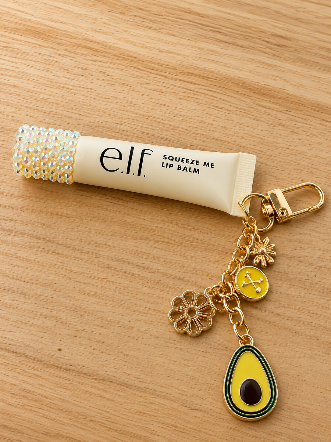 Hand-bedazzled lip balm charm keychain with rhinestones, playful charms, and gold hardware. A sparkly accessory that&