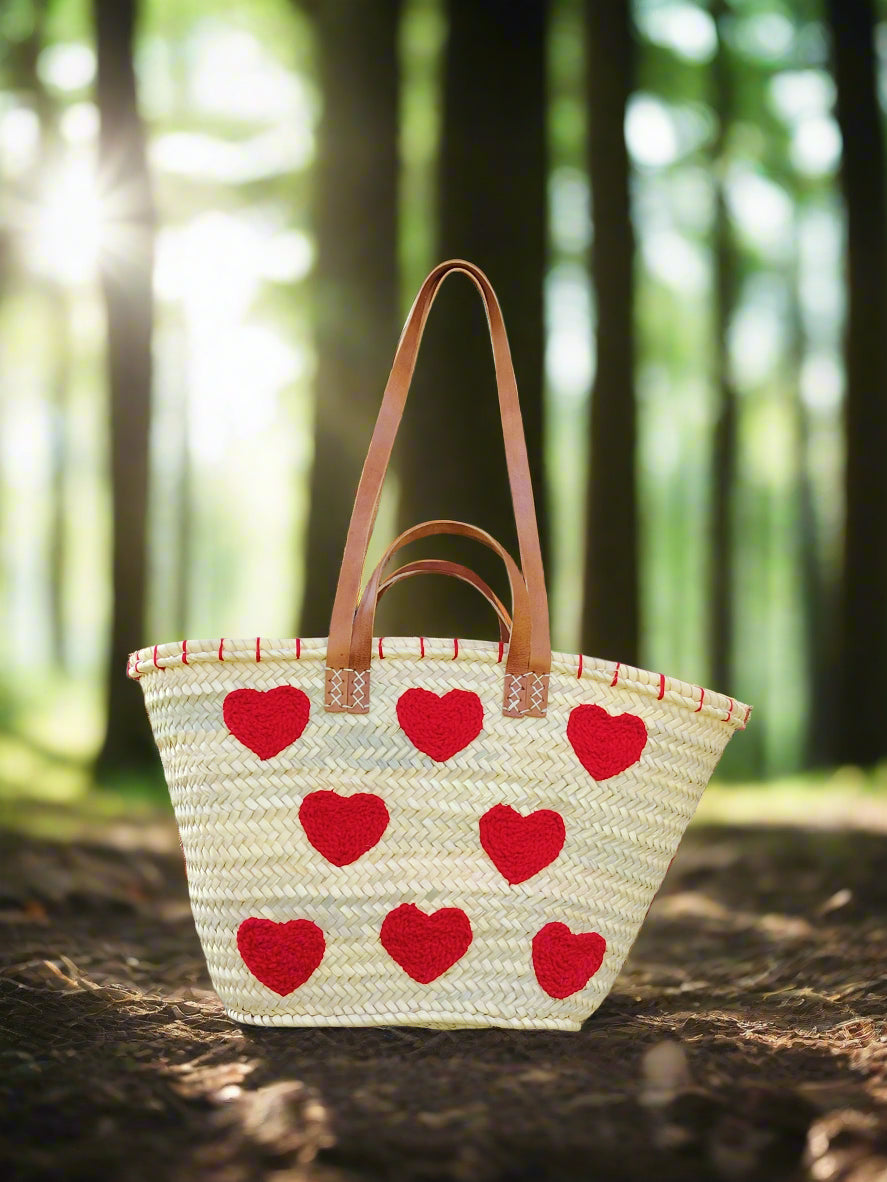 Handwoven straw tote with red crochet hearts and leather handles. Eco-friendly, artisan-made, and perfect for markets, gifting, or seasonal outings.