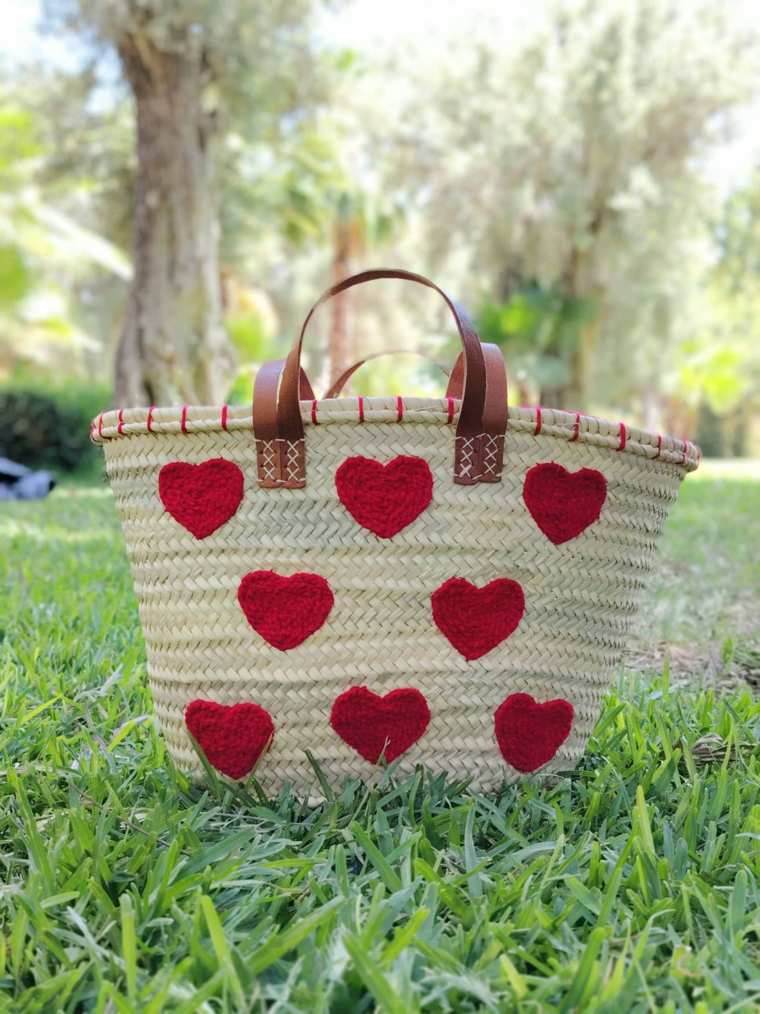 Handwoven straw tote with red crochet hearts and leather handles. Eco-friendly, artisan-made, and perfect for markets, gifting, or seasonal outings.