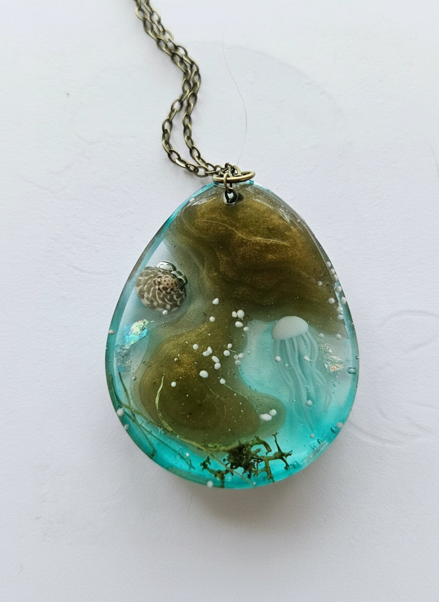 Sea Life Resin Pendant Necklaces by artist KStonely featuring shells, fish, jellyfish, and sea life miniatures in dreamy blue, brown, and gold ocean-inspired resin.
