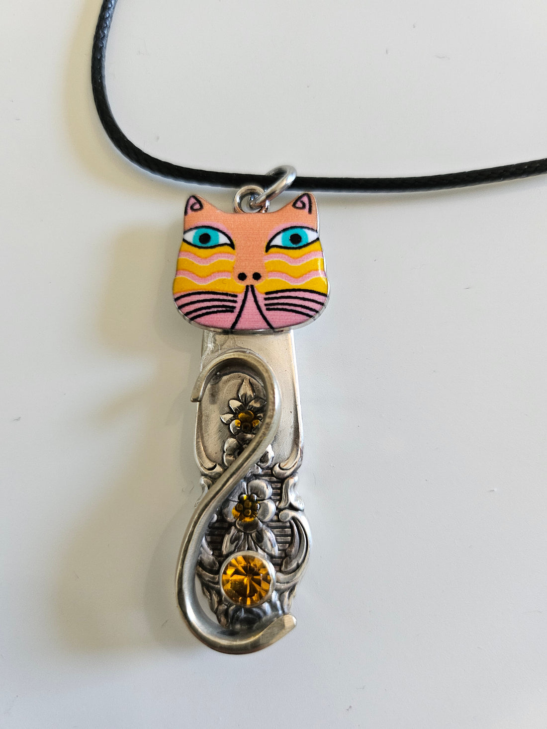 Handcrafted vintage silverware necklaces featuring enamel cat faces on adjustable satin cords. Made from 1951 Distinction and 1952 Primrose patterns.