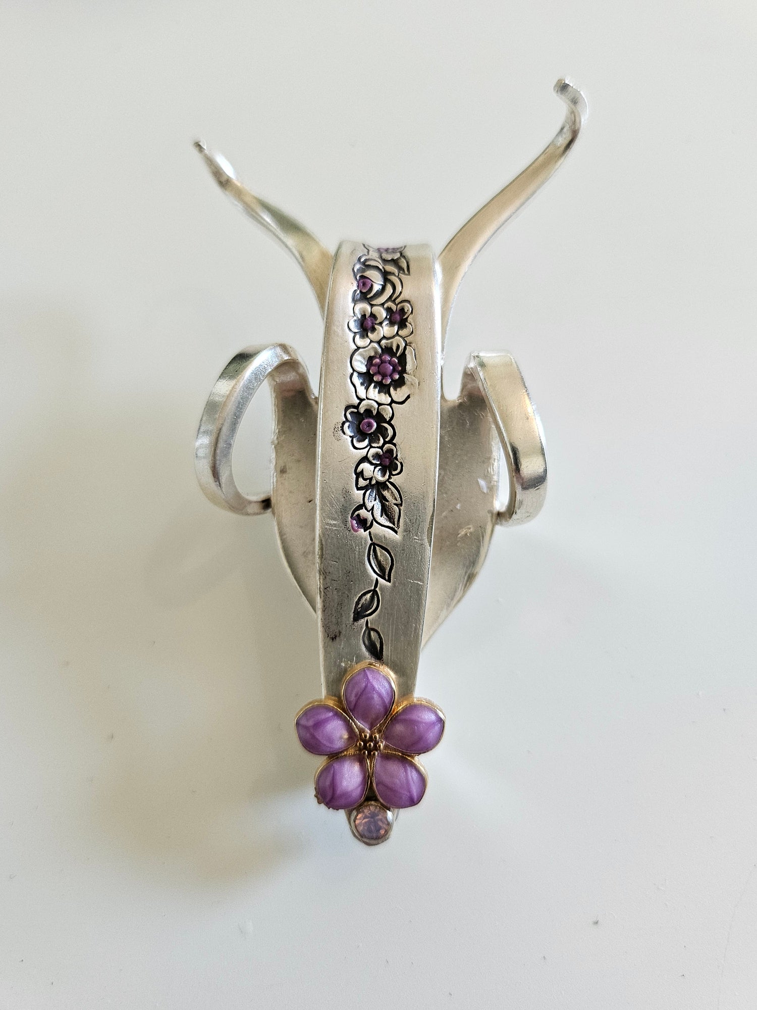 The Jeweled Lucky Fork Cricket is a whimsical, handcrafted sculpture made from repurposed vintage silverware. Each unique piece, shaped from antique forks, captures the charm of crickets—symbols of luck, prosperity, and protection. Adorned with jewels and aged patina, these one-of-a-kind collectibles add artistry, history, and positive energy to any space. 