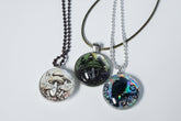 Handcrafted nature scene necklaces with real botanicals in iridescent and clear resin. Unique, wearable landscapes on chain or satin cord.