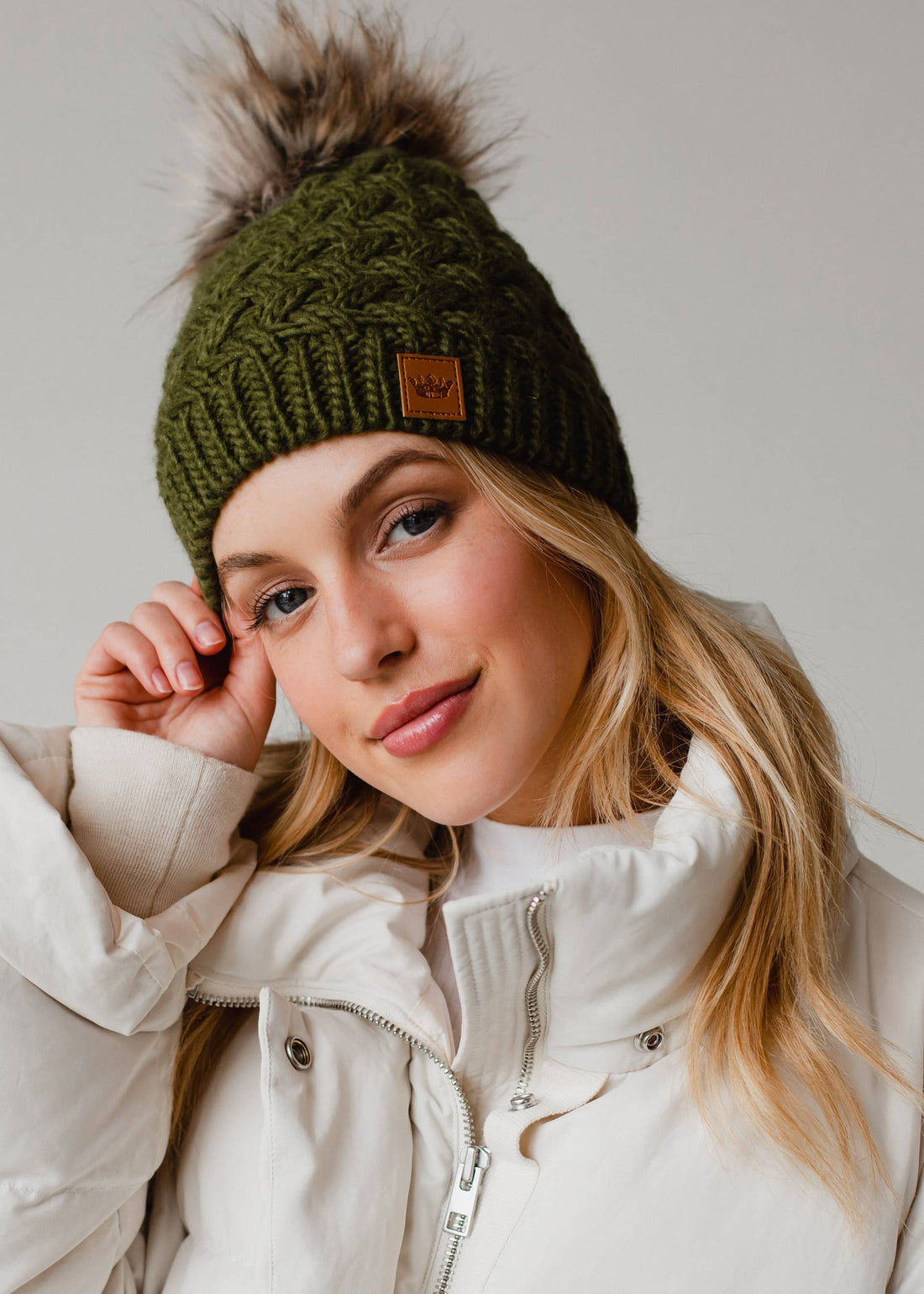 Olive green knit hat with natural faux fur pom. Cozy, stylish, and versatile—crafted from 100% acrylic for warmth and everyday boho-chic winter vibes.