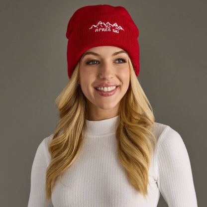 Red knit beanie with white embroidered Apres Ski text and graphic on the cuff. Fleece lined and made from 100% acrylic for cozy, playful winter style.