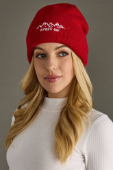 Red knit beanie with white embroidered Apres Ski text and graphic on the cuff. Fleece lined and made from 100% acrylic for cozy, playful winter style.