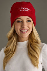 Red knit beanie with white embroidered Apres Ski text and graphic on the cuff. Fleece lined and made from 100% acrylic for cozy, playful winter style.