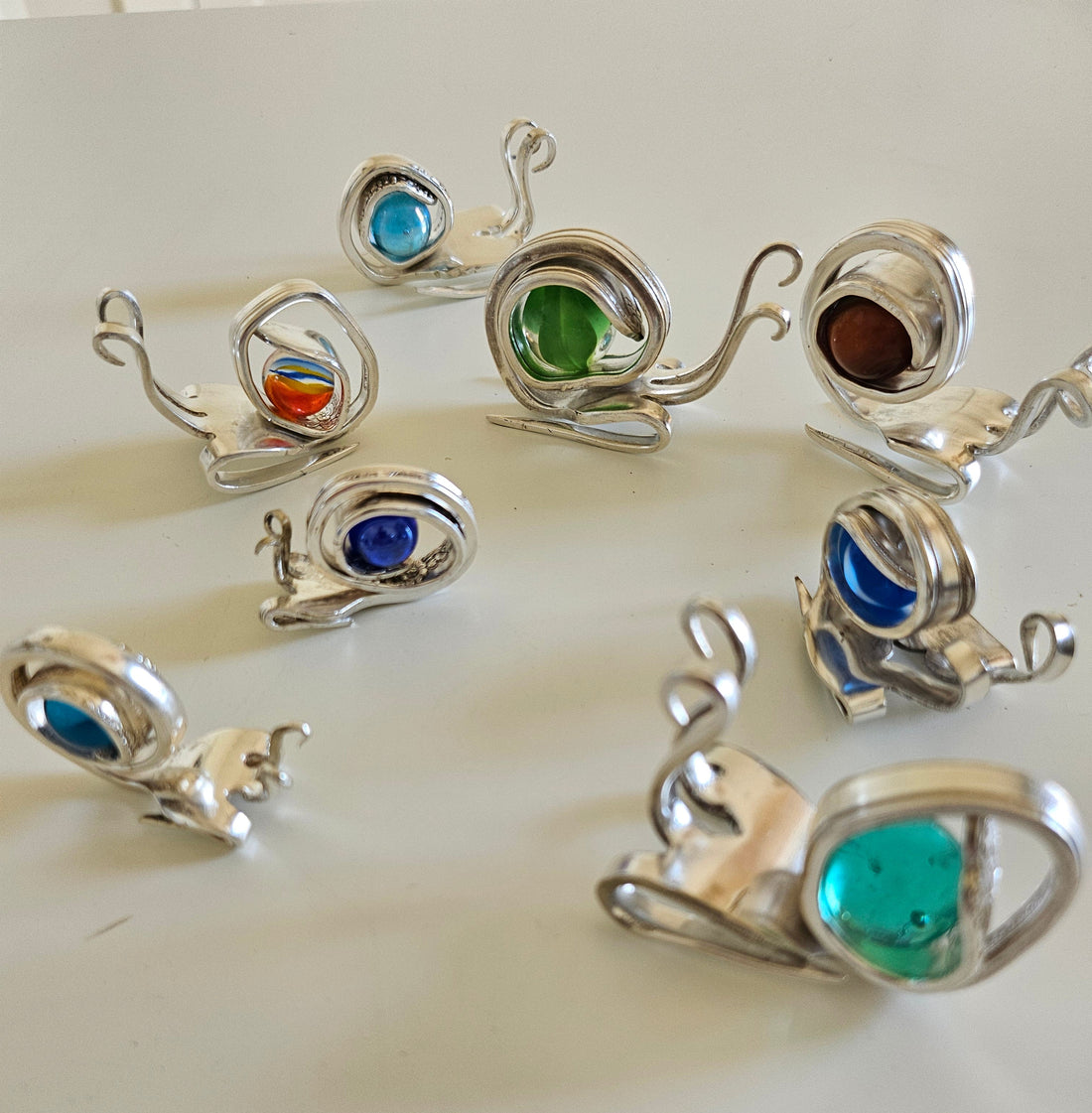 Handcrafted from vintage silverware, these whimsical snails feature shimmering glass orb shells—each a one-of-a-kind symbol of patience and charm.