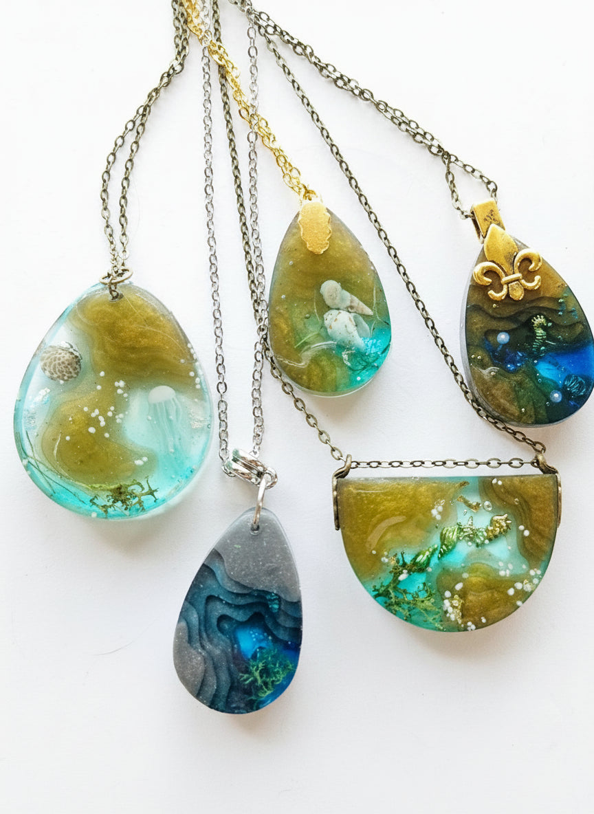 Sea Life Resin Pendant Necklaces by artist KStonely featuring shells, fish, jellyfish, and sea life miniatures in dreamy blue, brown, and gold ocean-inspired resin.