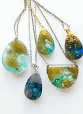 Sea Life Resin Pendant Necklaces by artist KStonely featuring shells, fish, jellyfish, and sea life miniatures in dreamy blue, brown, and gold ocean-inspired resin.
