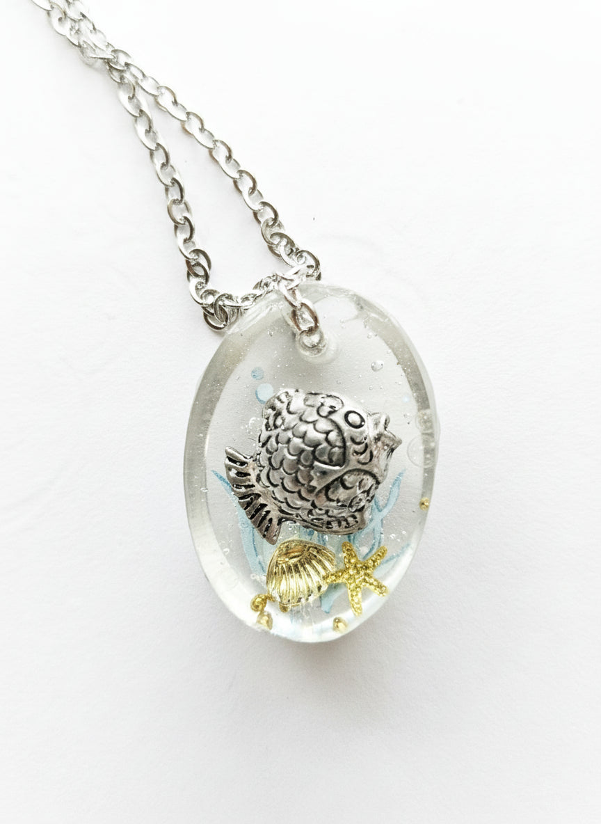 Sea Life Resin Pendant Necklaces by artist KStonely featuring shells, fish, jellyfish, and sea life miniatures in dreamy blue, brown, and gold ocean-inspired resin.