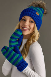 Royal blue and green striped knit hat with a natural-toned faux fur pom and cozy fleece lining. Made from 100% acrylic for warmth and colorful winter style.