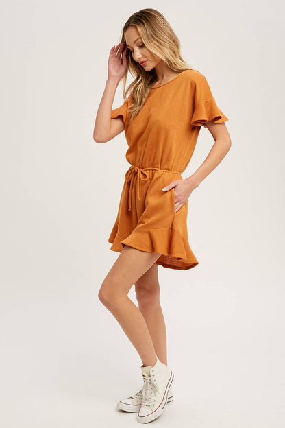 Soft French terry romper with ruffled sleeves, elastic waist, pockets &amp; back button closure. Comfy, cute, and perfect for sunny days or casual outings.