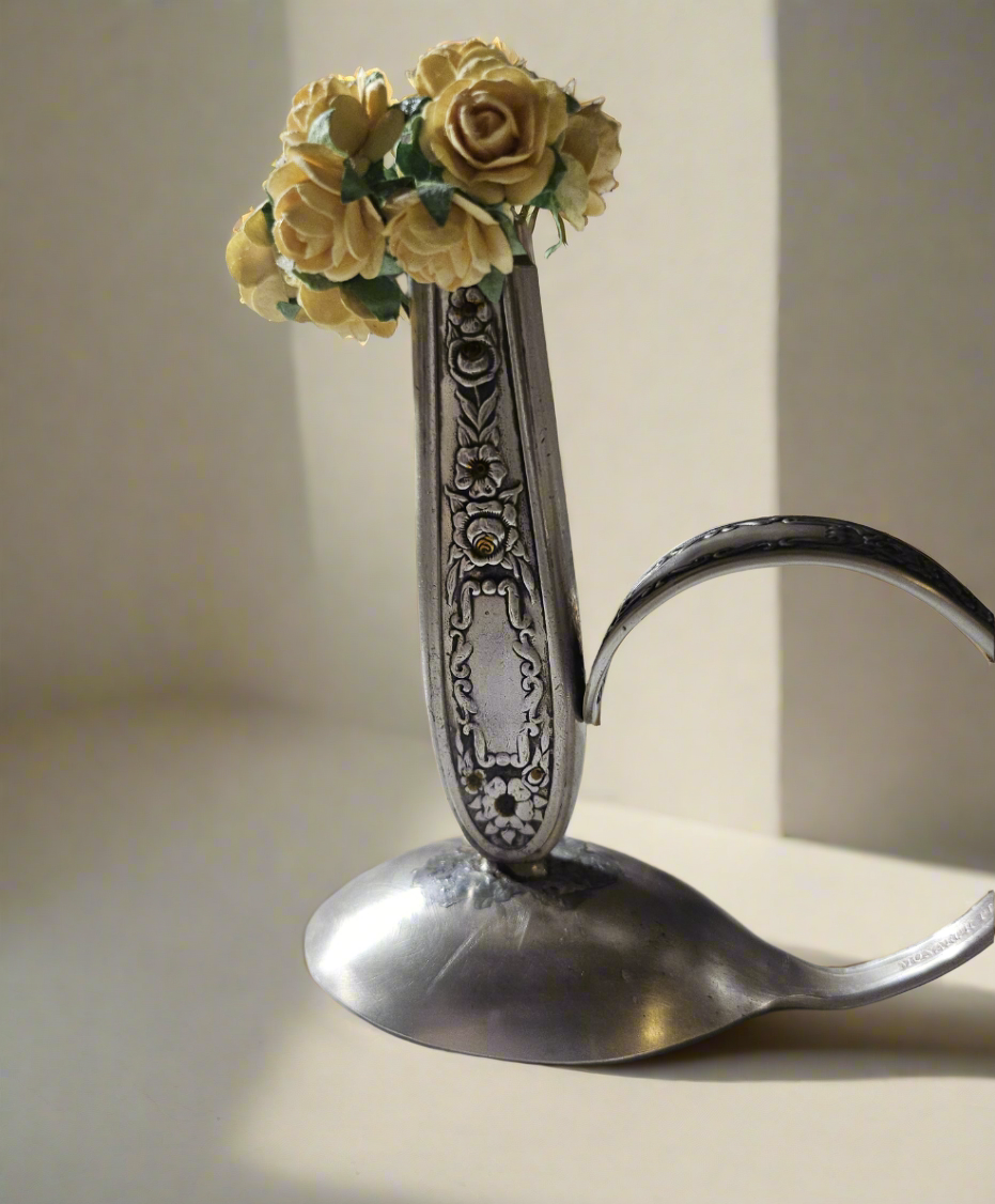 The Salvaged Silver Vintage Bud Vase is a handcrafted décor piece made from authentic Mildred 1936 antique silverware. Repurposed with artistry, it blends vintage charm with sustainability. Each vase is unique, making it a timeless accent for any space. A perfect gift for collectors and eco-conscious decorators, bringing history to modern homes. 
