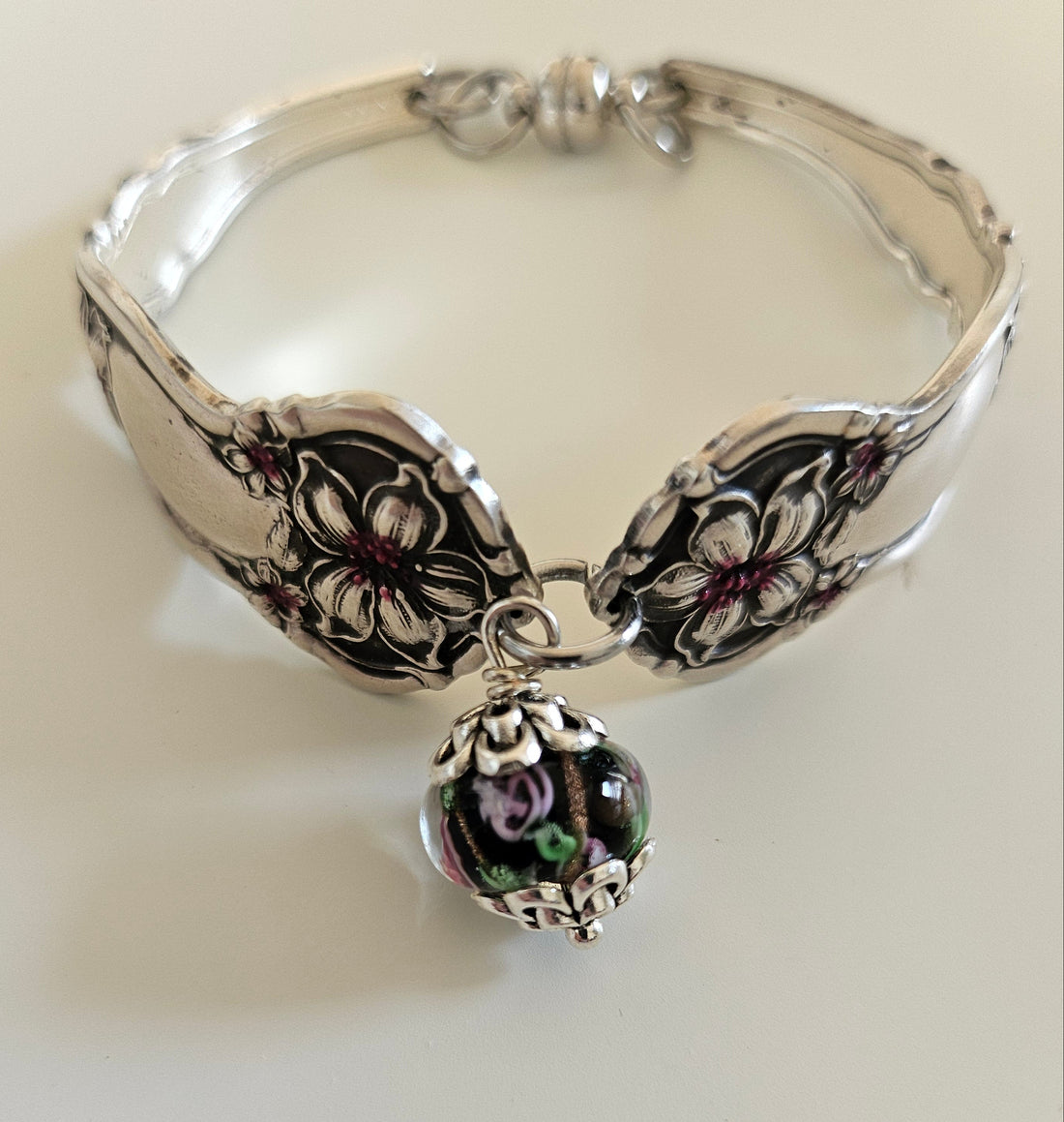 Handcrafted from 1910 Wm. Rogers silverware, this vintage Orange Blossom bracelet features glass beads, a magnetic clasp, and timeless floral charm.