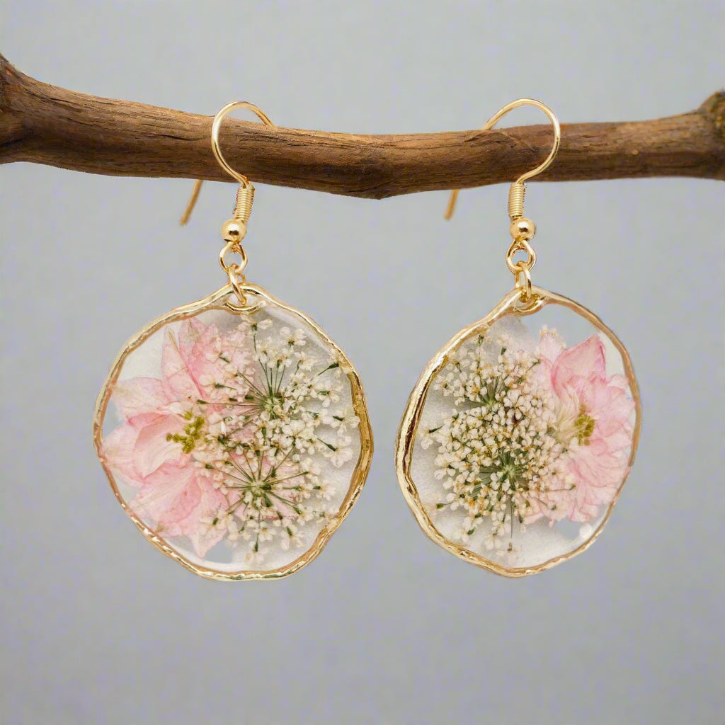 Blushing Bloom earrings feature real pink delphinium and Queen Anne’s Lace in clear resin with copper frames—lightweight, romantic, and naturally one-of-a-kind.